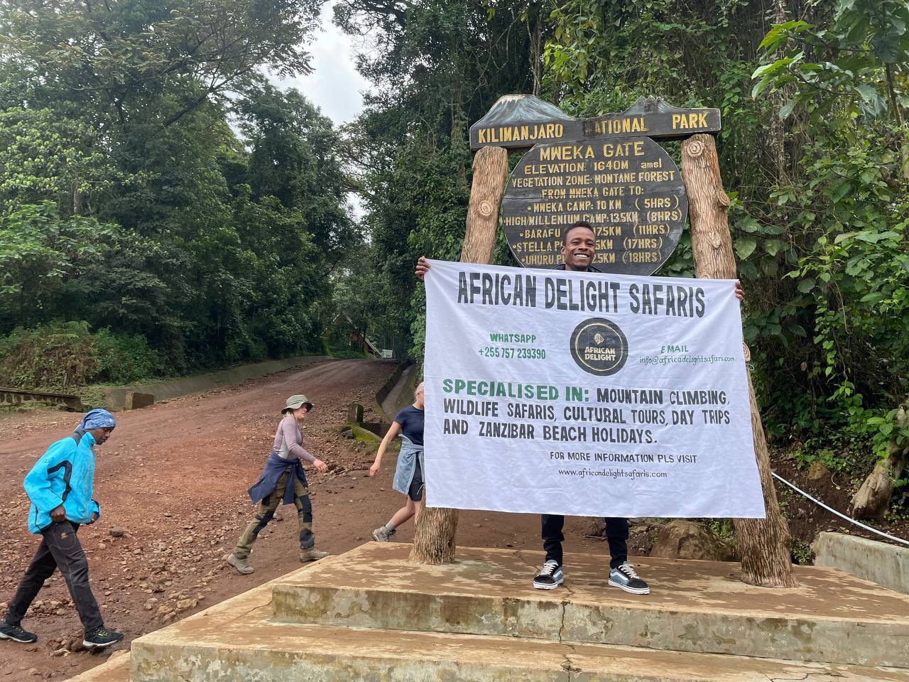 Company staff with banner infront of Mweka Gate Trail of Mt. Kilimanjaro