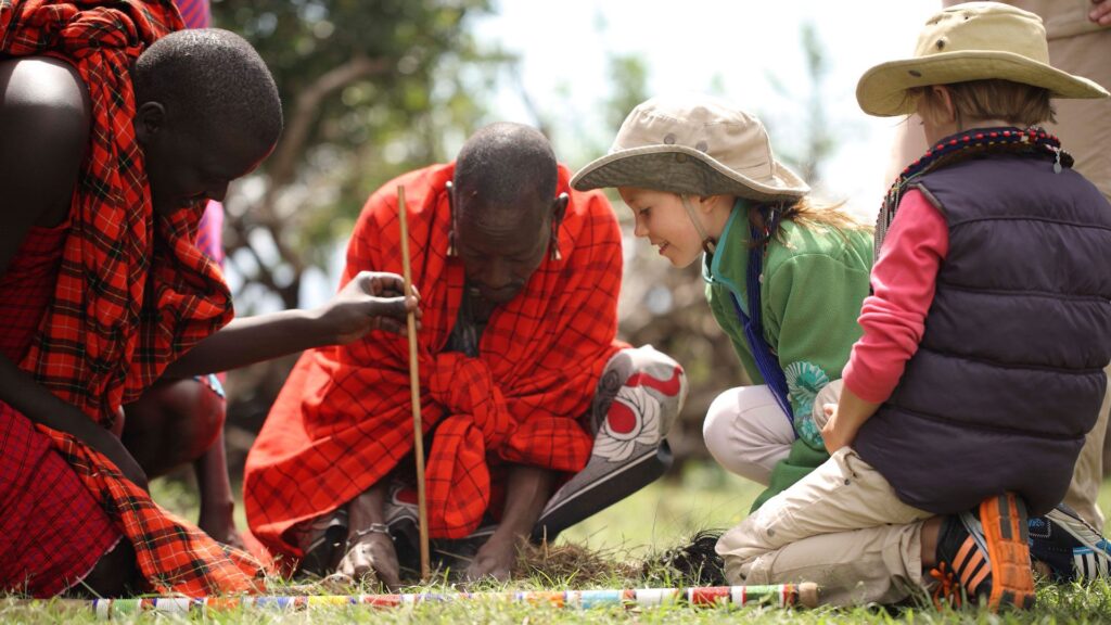Maasai warrior making fire with children during a cultural tour in Tanzania