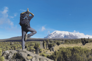 hiker doing a yoga pose on mt. kilimanjaro marangu route