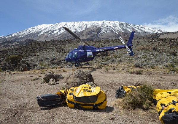 Kilimanjaro travel insurance helicopter in-front of Mt. Kilimanjaro