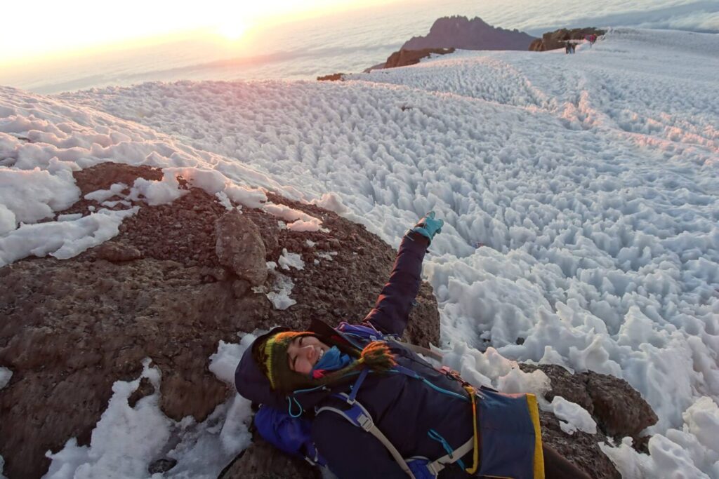 A tired hiker resting on snow at kilimanjaro summit