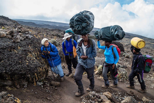 female porters of Mt. Kilimanjaro passing by tourists