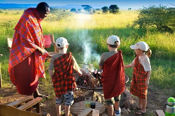 kids enjoying a barbecue with a maasai warrior