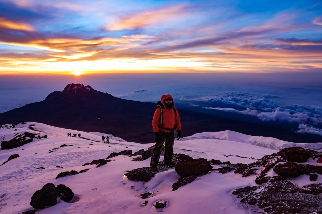Hiker on mt. kilimanjaro summit during sunrise