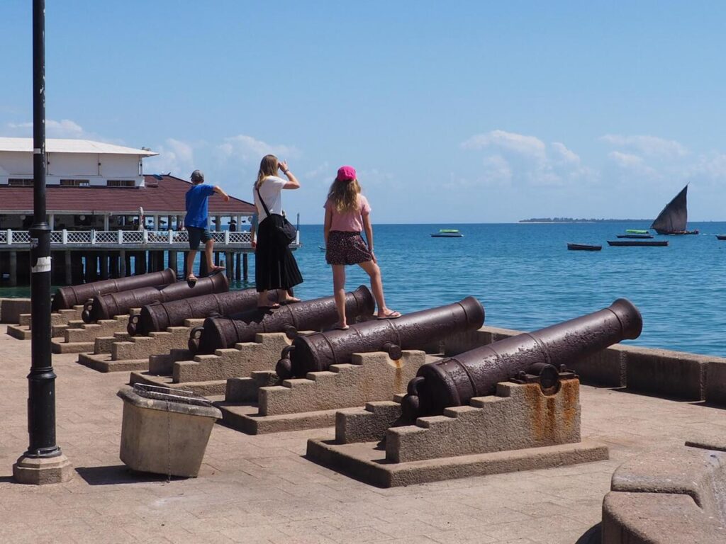 tourist standing on colonial cannons at zanzibar beach