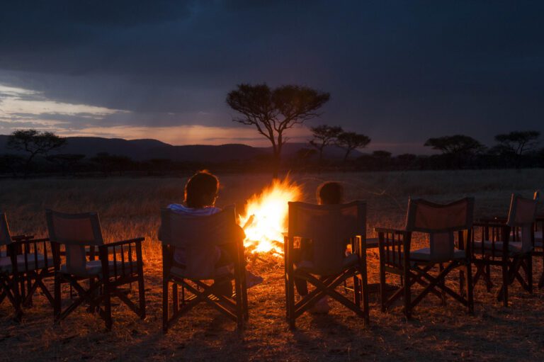 a couple sitting a campfire in Serengeti